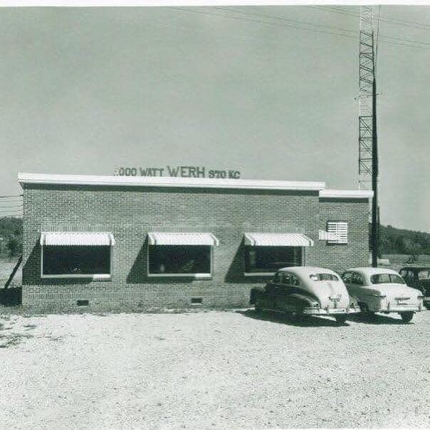 Archival photograph of WERH Radio’s brick building, three striped awnings, and radio tower